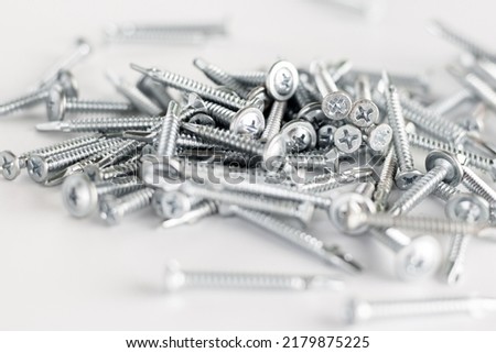 Tapping screws made of steel on gray background, metal screw, iron screw, chrome screw, screws as a background, wood screw, concept industry. copy space for text.