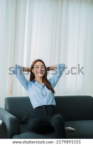 Attractive beautiful Asian woman relaxing on the sofa in the living room at home. vertical picture