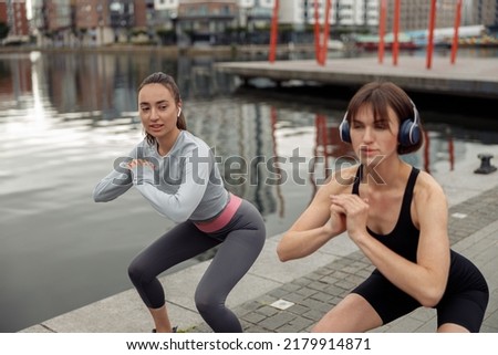 Beautiful sportive women doing fitness exercise on city background at morning