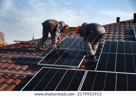 workers installing solar panels on the roof Royalty-Free Stock Photo #2179921913