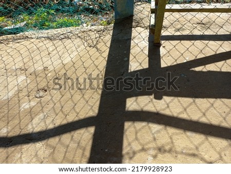 up close on the dusty concrete floor of the street, with the shadow of a dramatic link chain fence, on the street