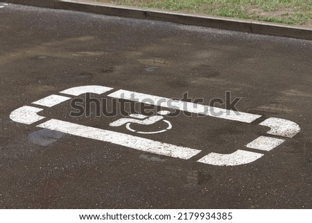 The handicapped parking sign is painted white on the road surface.