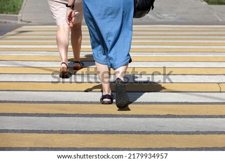 Women crossing the street, female legs on pedestrian crossing. Concept of road safety in summer