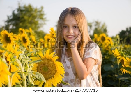 Little girl on the field with sunflowers blurred background