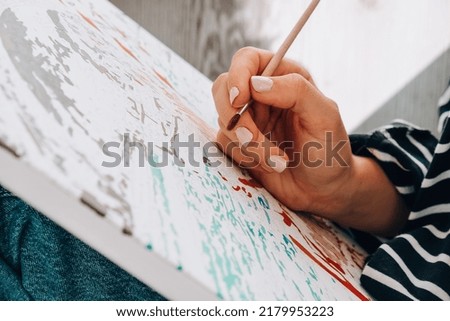 Painting on canvas by numbers and numbered jars of paint. Woman draws with a brush painting by numbers on canvas. Creative hobby. Painting for beginners. Leisure activity for stay home lockdown