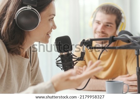 Young man and woman wearing headphones and doing a live podcast for their channel, communication and technology concept