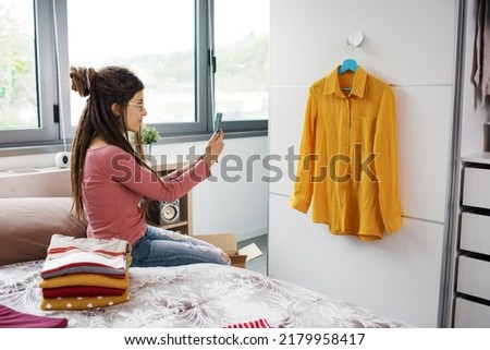 Woman taking picture of her used clothes, she is selling her clothing online