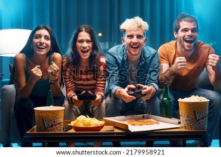 Cheerful group of friends playing video games together at home, leisure and entertainment concept Royalty-Free Stock Photo #2179958921