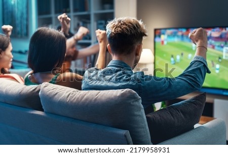 Group of young friends watching a football match on TV together and cheering for their team Royalty-Free Stock Photo #2179958931