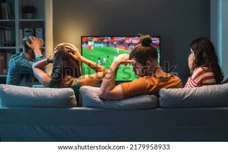Sad disappointed group of friends watching a football match on TV, their team is losing the match Royalty-Free Stock Photo #2179958933