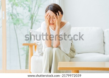 Japanese woman holding her head Royalty-Free Stock Photo #2179972039