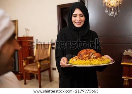 Arabian woman  holding rice and chicken during ramadan, Arabian mother with hijab preparing food  Royalty-Free Stock Photo #2179975663