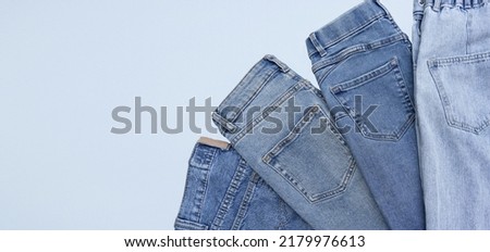 Lots of jeans pants in a stack. Denim background. The concept of buying, selling, shopping and trendy modern clothes. Royalty-Free Stock Photo #2179976613