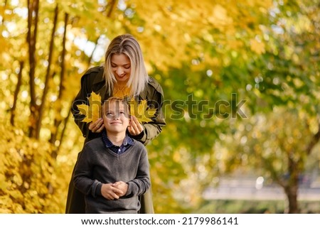 Mother and son have fun together. Family walk in the park in autumn. Hello October. Thanksgiving holiday. Happy motherhood. Childhood. Maple leaves. Fun play together. Leaf ears. Fall Royalty-Free Stock Photo #2179986141