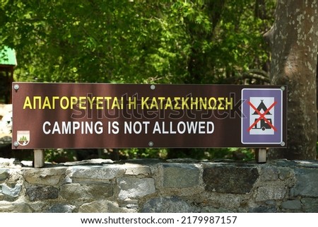 Board with information in English and Greek CAMPING IS NOT ALLOWED and pictogram in Troodos Mountains in Cyprus