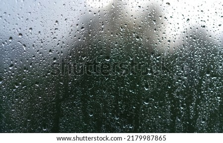 Raindrops on the window on a gloomy day by the bad weather