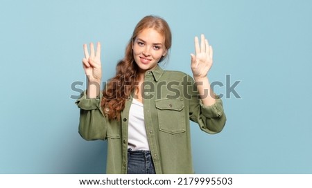 blonde pretty woman smiling and looking friendly, showing number eight or eighth with hand forward, counting down
