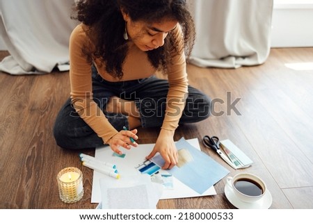 Young brunette african american woman creating her Feng Shui wish map using scissors. Dreams and wishes Royalty-Free Stock Photo #2180000533