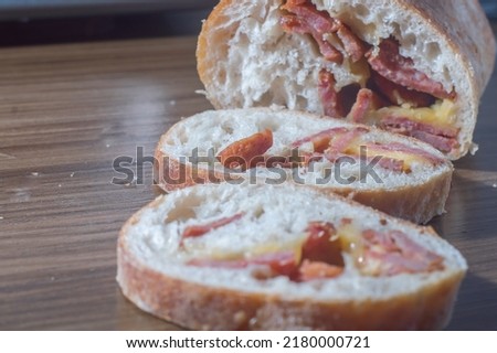 Handmade bread with natural fermentation stuffed with calabrian sausage"Linguiça calabresa"and cheese, on a wooden table with a slice cut and copy space for text.