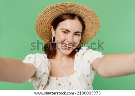 Close up young happy cheerful woman she 20s wears white dress hat doing selfie shot pov on mobile cell phone isolated on plain pastel light green background studio portrait. People lifestyle concept