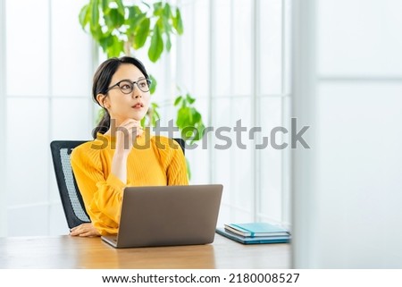 Young Asian woman using a laptop PC in modern office. Royalty-Free Stock Photo #2180008527