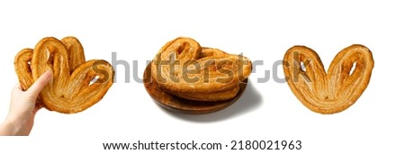 Sweet braided palmiers pastry, palm heart or elephant ear on wooden plate isolated. French puff pastry or pate feuilletee Royalty-Free Stock Photo #2180021963