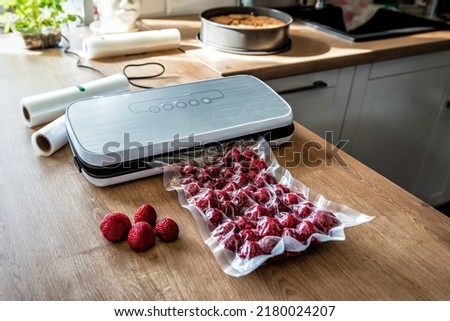 Vacuum strawberries packaging for long-term storage. They use of a vacuum sealer for long-term storage of products. Vacuum packing machine Royalty-Free Stock Photo #2180024207