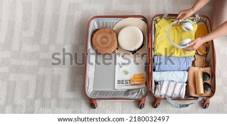 Woman packing suitcase at home, top view. Travel concept Royalty-Free Stock Photo #2180032497