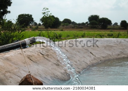 Water coming out of a tube well and flowing in the agricultural fields,water pump and tank with a huge flow of fresh water for irrigating fields,farming concept