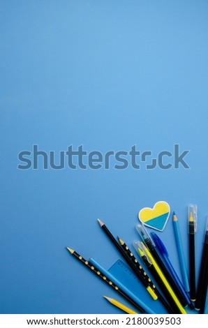 Flatlay right vertical  composition black pencils, yellow pencil, blue ruler, patch heart and blank blue background