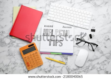 Flat lay composition with text Helpful Tips in notebook on white marble table