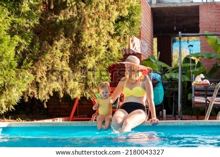 Summer vacation. Plus sized woman and little cute girl sitting by a pool and refreshing. Family relax.