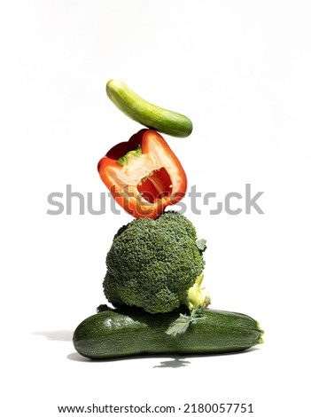 Pyramid of balancing vegetables: broccoli, zucchini, cucumber, bell pepper on a white background. Equilibrium floating food balance.