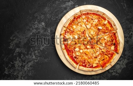 Tasty hawaiian pizza with chicken and pineapple on wooden cutting board on a dark background. food delivery, place for text, top view.