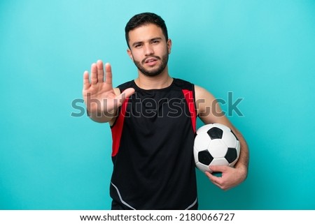Young football player Brazilian man isolated on blue background making stop gesture