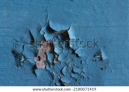 Blue peeling paint on the wall. Old concrete wall with cracked flaking paint. Weathered rough painted surface with patterns of cracks and peeling. High resolution texture for background and design. Royalty-Free Stock Photo #2180071419