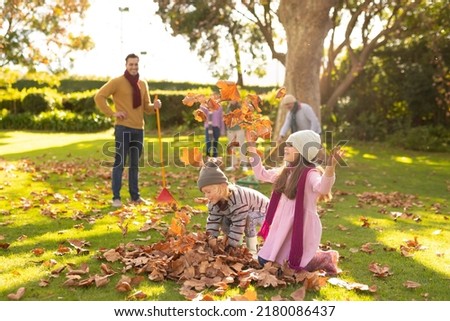 Image of happy multi generation caucasian family having fun with leaves in autumn garden. Family and spending quality time together concept.