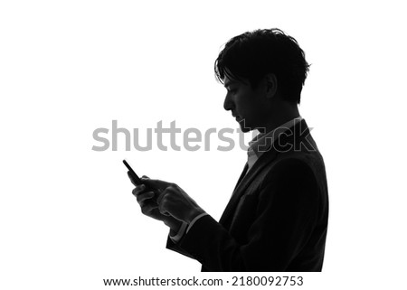 Silhouette of young businessperson using a smart phone.
