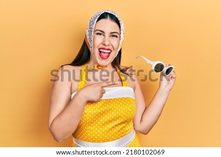 Young hispanic woman wearing pin up style smiling happy pointing with hand and finger 