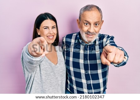 Hispanic father and daughter wearing casual clothes pointing to you and the camera with fingers, smiling positive and cheerful 