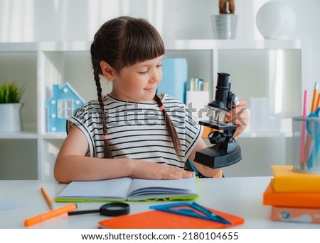 School girl with microscope for school education at home.