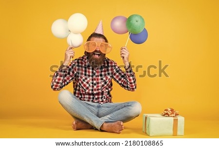 holiday celebration. bearded mature man celebrate birthday party. cheerful man in bday hat hold holiday balloons. gifts and presents concept. have a happy holiday. party time. happy birthday to you
