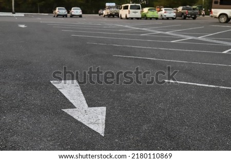 Closeup of arrow on asphalt ground of the parking lot with natural background in the evening. The traffic sign show the symbol of safty and right direction to the goal.