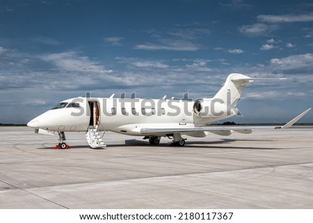 Modern white corporate business jet with a lowered gangway door at the airport apron Royalty-Free Stock Photo #2180117367