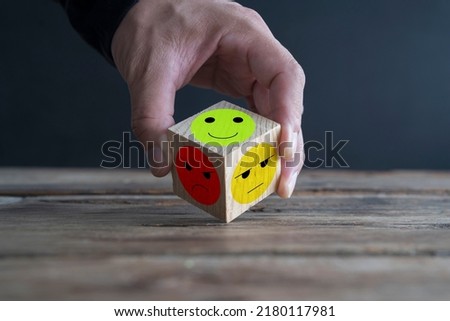 Businessman holds wooden blocks with sad and happy emotion icon emoticon set, vote symbol set.