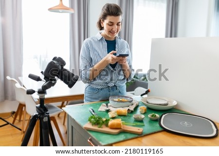 blogging and people concept - happy smiling female photographer or food blogger with camera and smartphone photographing soup in kitchen at home
