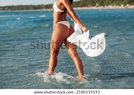 people, summer and swimwear concept - young woman in bikini swimsuit with cover-up on beach
