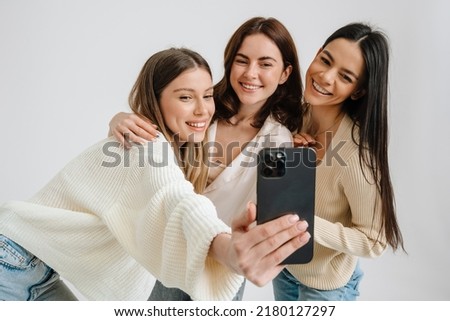 Three beautiful brunette women smiling and taking selfie photo isolated over white background