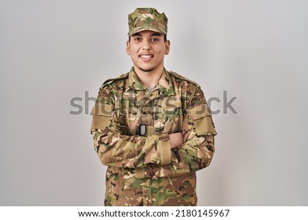 Young arab man wearing camouflage army uniform happy face smiling with crossed arms looking at the camera. positive person. 