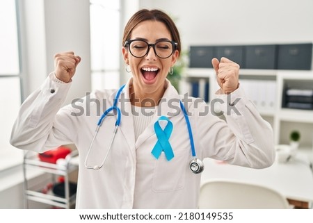 Young brunette doctor woman wearing stethoscope at the clinic excited for success with arms raised and eyes closed celebrating victory smiling. winner concept. 